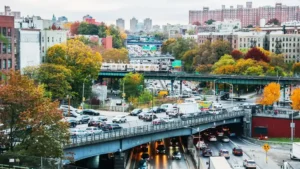 An autumn view of New York City traffic and elevated subway trains, highlighting the daily commute near West Bronx transit routes and local dispensaries.